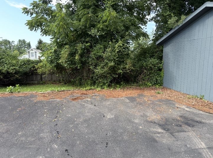 Same fence line cleared back to open ground beside a blue outbuilding after brush clearing, Christiansburg, VA